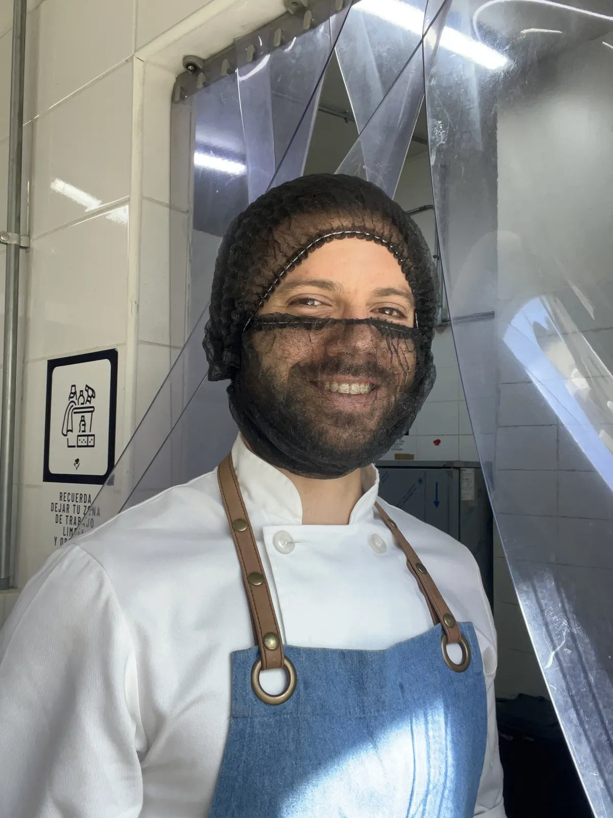 Nico con cofia y delantal en la cocina de producción